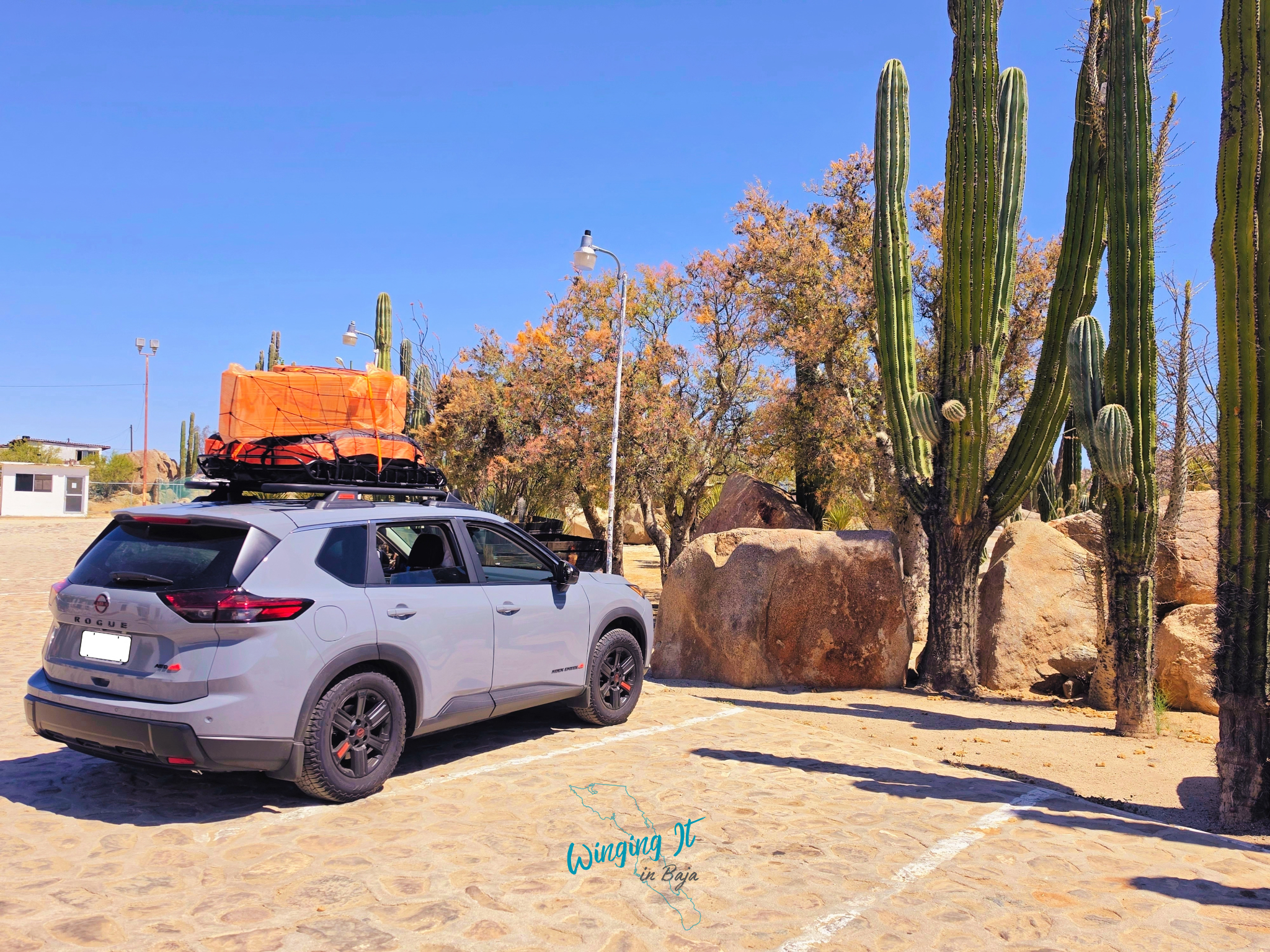 Nissan Rogue fully packed, parked in a parking lot alongside cacti in front of the hotel.